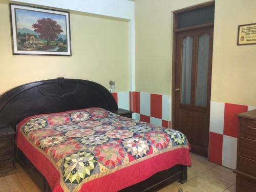 Un dormitorio con una cama con una colcha colorida. en HOSTAL FAMILIAR FG, en Cochabamba