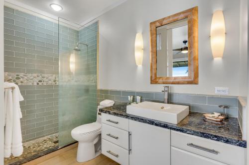 a bathroom with a sink and a toilet and a mirror at Poipu Shores 403A in Koloa
