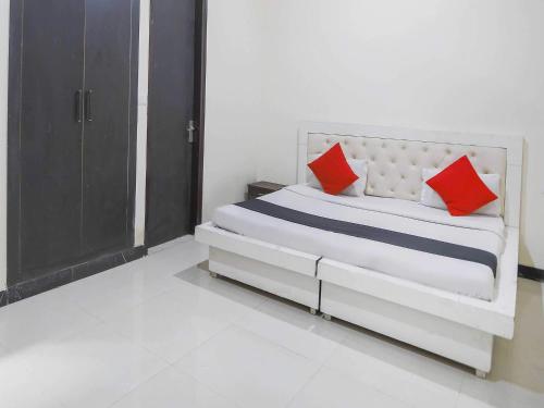 uma cama branca com almofadas vermelhas num quarto em Super OYO Flagship GRANDEUR HOTEL em Indirapuram