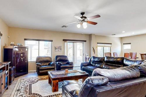 a living room with leather furniture and a ceiling fan at Poolside Tranquility in Queen Creek