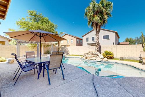 a table and chairs with an umbrella next to a pool at Poolside Tranquility in Queen Creek