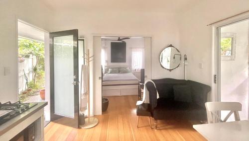 a living room with a piano and a bedroom at The White Cottage Byron Bay in Suffolk Park