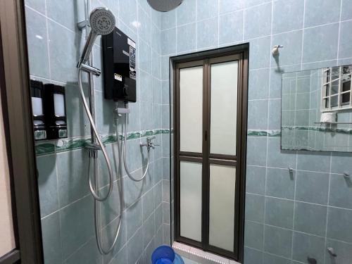een douche in een badkamer met een glazen deur bij Mutiara Villa Homestay - Comfort Away From Home in Merlimau