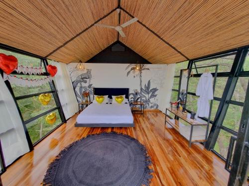 a bedroom with a bed in a room with windows at Tree House Glamping in Yopal