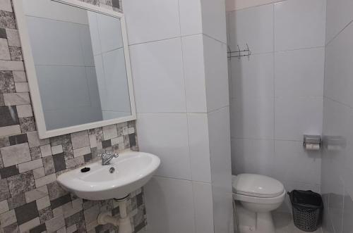 a white bathroom with a sink and a toilet at ARIMBI GUEST HOUSE in Batu