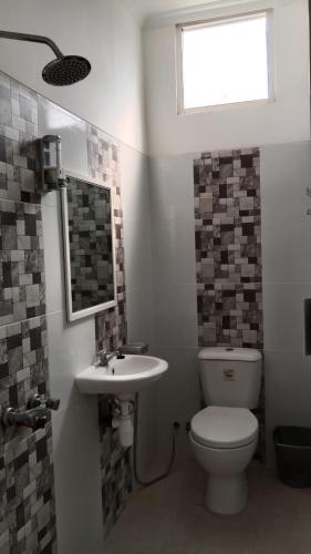 a bathroom with a toilet and a sink and a window at ARIMBI GUEST HOUSE in Batu