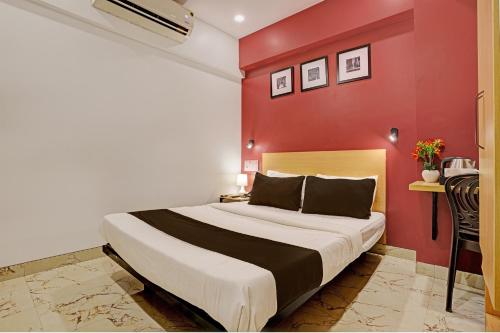 1 dormitorio con 1 cama grande y pared roja en Collection O Dsp Hotels, en Ghansoli