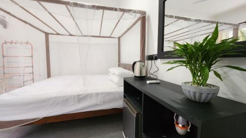 a bedroom with a bed and a black desk with a plant at E Seven House in Dickwella