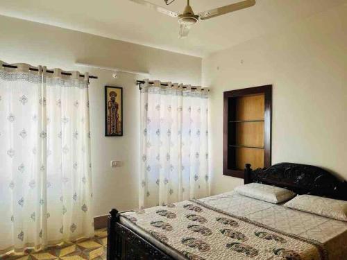 een slaapkamer met een bed met witte gordijnen en een raam bij Stay @ Race Course Road, BLR in Bangalore