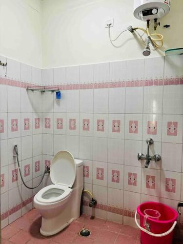 een badkamer met een toilet in een roze en witte tegelmuur bij Stay @ Race Course Road, BLR in Bangalore