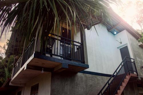 a building with a balcony and a palm tree at Olive Launch in Weligama