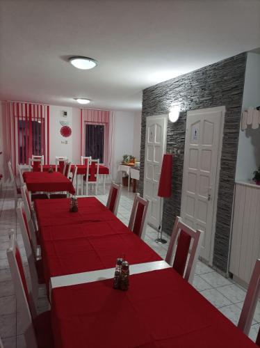un comedor con mesas y sillas rojas y una pared de ladrillo en Zoltán & Erika Panzió Parajd, en Praid