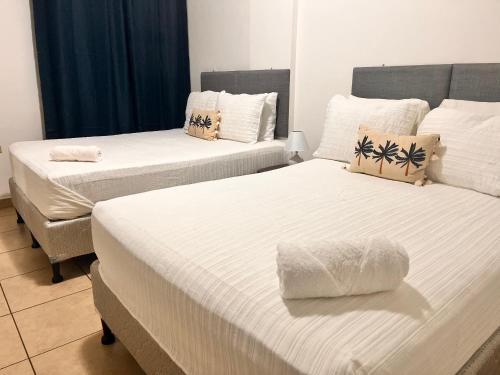 2 camas en una habitación de hotel con sábanas blancas en Apartamentos Trebol, en Comayagua