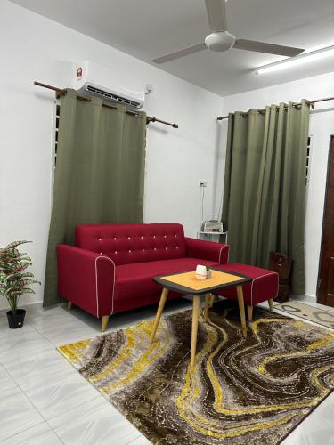 ein Wohnzimmer mit einem roten Sofa und einem Tisch in der Unterkunft Paddy View Homestay Kangar in Kangar