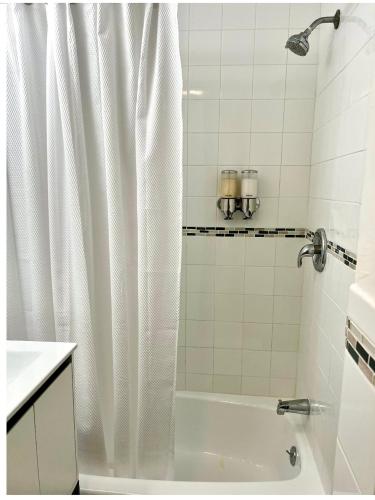 a bathroom with a white shower curtain and a tub at 2-A Diamond in Yonkers in Yonkers