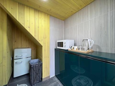 a small kitchen with a counter with a microwave at An Gimnyeong Stay in Jeju