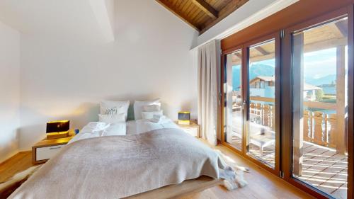 a bedroom with a bed and a large window at Family holiday home Tgiampi Sot Lantsch Lenzerheide in Lenz