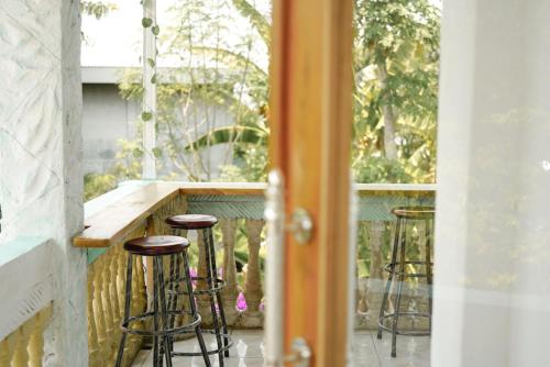 eine Veranda mit Hockern und eine Bar auf dem Balkon in der Unterkunft Bajo Bunkhouse in Labuan Bajo