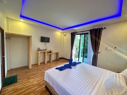 una camera da letto con un letto bianco con luci blu di Lanta Living bungalow a Ko Lanta