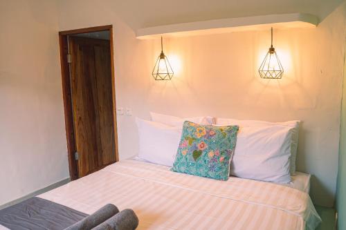 a bedroom with a bed with two lights on the wall at Gili Divers Hotel in Gili Trawangan