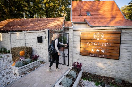 a woman standing at a gate in front of a building at Szanna Apartman in Doboz