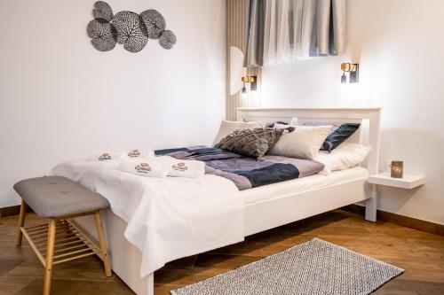um quarto com uma cama branca e um banco em Szanna Apartman em Doboz