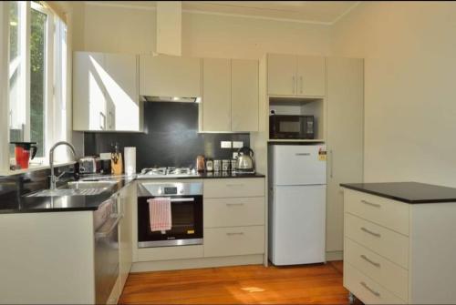 een witte keuken met een wastafel en een koelkast bij Morere cottage in Morere