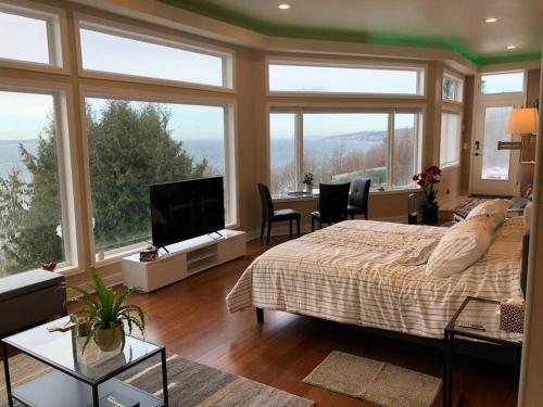 a bedroom with a bed and a room with windows at Romantic Spacious Suite with Salish Sea & Mountain Views at Seattle Luxury Estate in Seattle