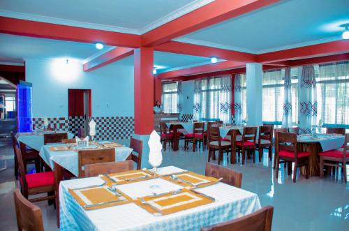 un comedor con mesas, sillas y ventanas en Kinindo Light Hotel en Buyumbura