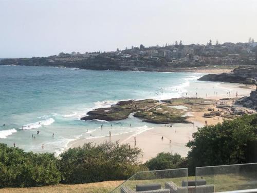 a group of people on a beach near the ocean at Tamarama Beachfront Apartment on Bondi to Bronte Walk in Sydney