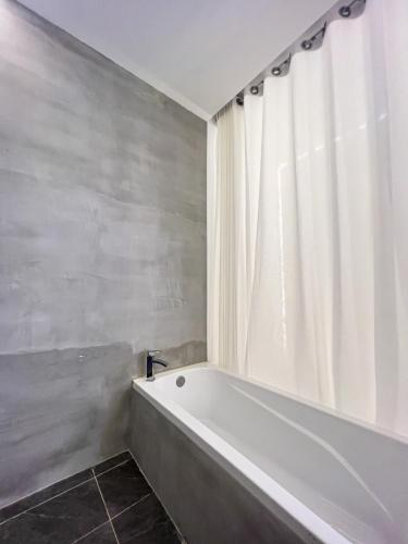 a white bath tub in a bathroom with a shower curtain at K-Road in Phnom Penh