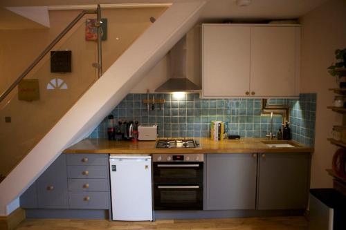 a kitchen with white cabinets and a staircase at Inviting & Secluded 1BD House w Patio - Peckham! in London