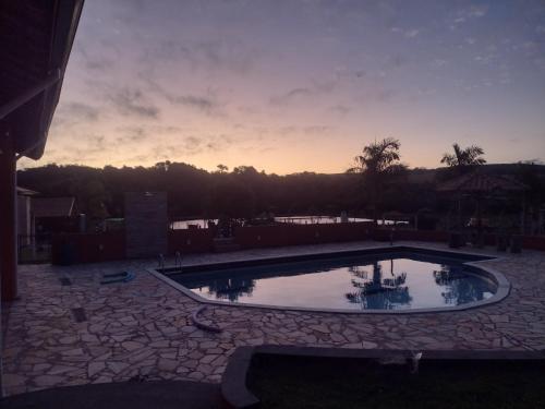 une grande piscine avec un coucher de soleil en arrière-plan dans l'établissement Pesqueiro & Chácara Moenda, à Itapetininga