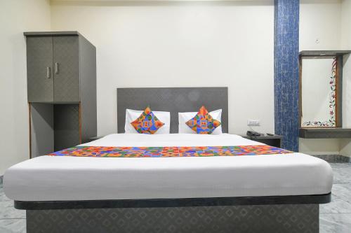 1 dormitorio con 1 cama grande y almohadas coloridas en FabHotel Shree Khatu Shyam Palace, en Indore