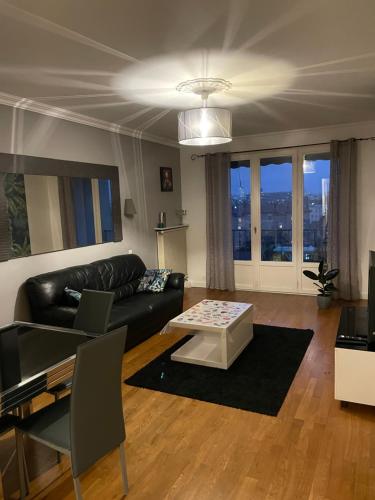 sala de estar con sofá de cuero negro y mesa en Logement T3 avec jolie vue dégagée, en Villeurbanne