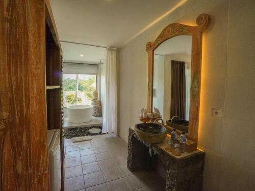 uma casa de banho com um lavatório e um espelho em The Nenggala Suite em Tegalalang