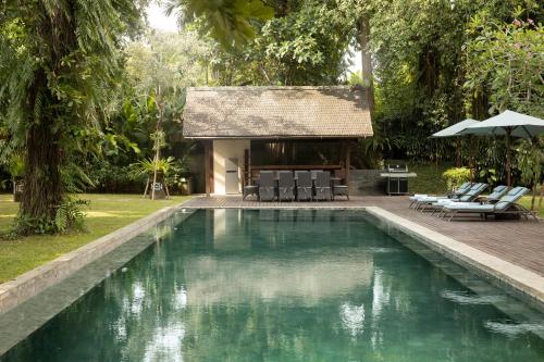 a swimming pool in a yard with a house at Villa Tirtadari by Nakula in Canggu
