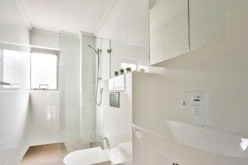 a white bathroom with a toilet and a shower at Superb 3 Bedroom Apartment Surry Hills in Sydney