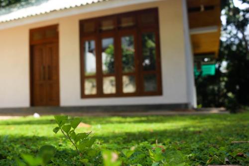 a house with a door and a yard with green grass at Cinnamon eco villa in Hikkaduwa