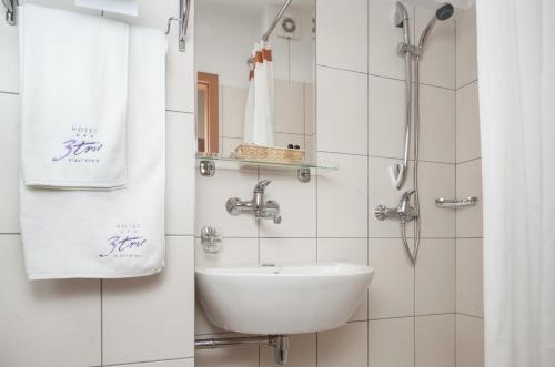 a bathroom with a sink and a shower with towels at Comfort by Trio in Białystok
