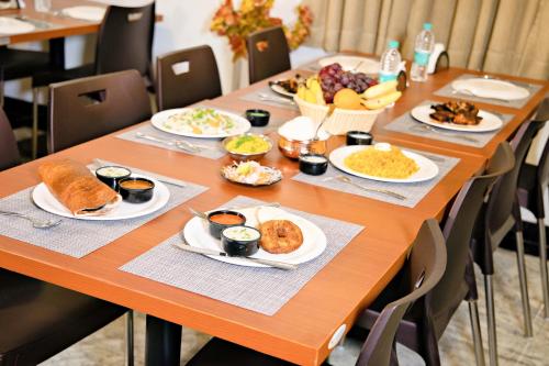 una larga mesa de madera con platos de comida. en Hotel Grand Villa en Yelahanka