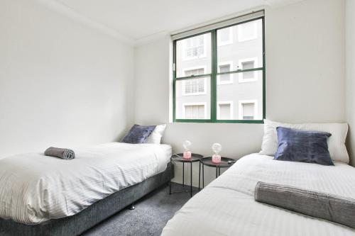 two beds in a room with a window at Stylish 2 Bedroom Apartment Chippendale in Sydney