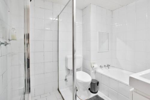 y baño blanco con aseo y ducha. en Stylish 2 Bedroom Apartment Chippendale en Sídney