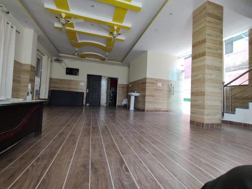 a large room with a wooden floor and a yellow ceiling at Hotel Aman in Rishīkesh