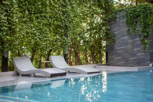 two chairs sitting next to a swimming pool at ISTY Design Hotel in Chiang Mai