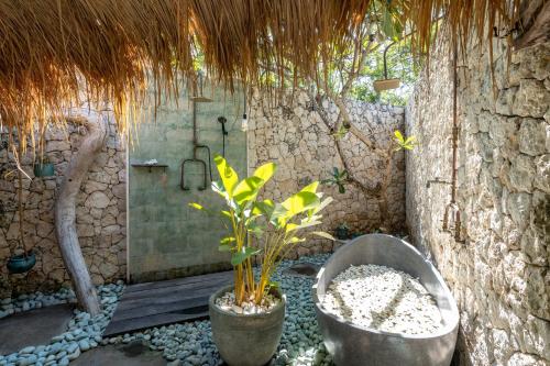 a bathroom with a shower and a tub with a plant at Laguna Biru in Nusa Lembongan