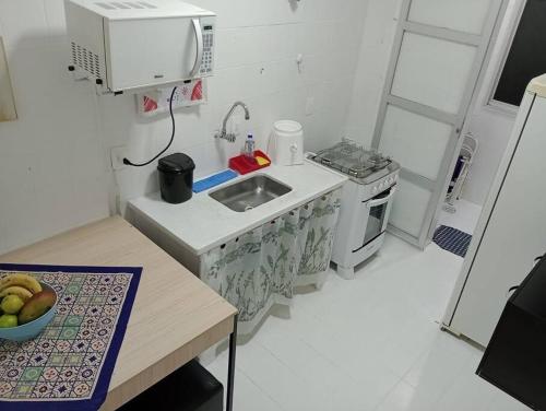 een kleine keuken met een spoelbak en een fornuis bij Apartamento Pé Na Areia in Mongaguá