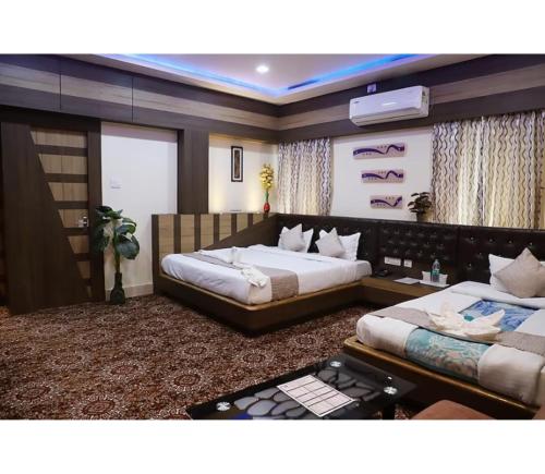a bedroom with two beds and a tv on the wall at Hotel Janvi International Inn, Muzaffarpur in Muzaffarpur