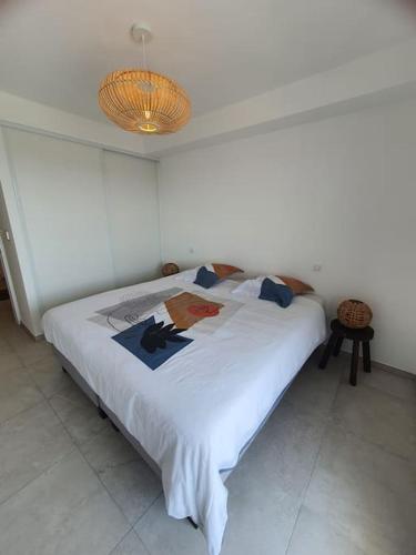 - un lit blanc dans une chambre avec une lampe dans l'établissement Bleu Odysée Appartement 2 chambres, terrasse, équipé climatisation, place de parking à disposition, à Canet