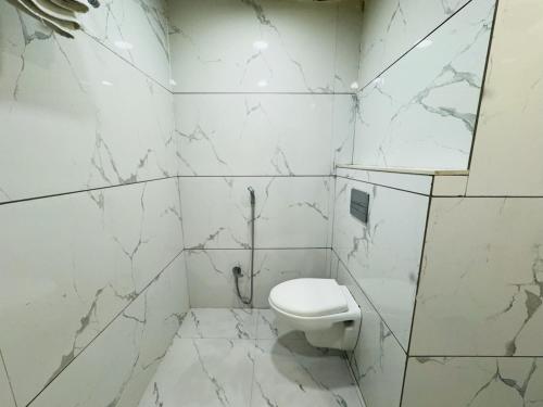 a white bathroom with a toilet and marble walls at Hotel shree mahakal krapa in Ujjain
